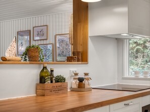 A kitchen with a wooden countertop, a built-in shelf with framed artwork, and a window with a view of greenery. - "Waghn" -  from the sea by Interhome (Hadsund)