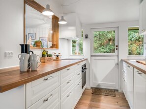 A modern kitchen with white cabinetry, wooden countertops, and a view of greenery outside. - "Waghn" -  from the sea by Interhome (Hadsund)