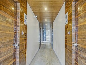 Un pasillo con paneles de madera en las paredes, suelo de mármol e iluminación empotrada en el techo.