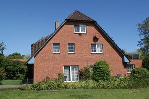 Ein zweistöckiges Ziegelhaus mit Satteldach, zahlreichen Fenstern und einem sichtbaren Schornstein.