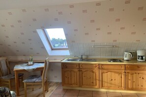 Eine Küche mit Oberlicht, Holzschränken, einer Arbeitsplatte und einem Essbereich mit Stühlen.