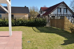 A residential area with a house featuring a gabled roof and a wooden fence. - Holiday apartment with 2 bedrooms (Wittenbeck\/Kühlungsborn)