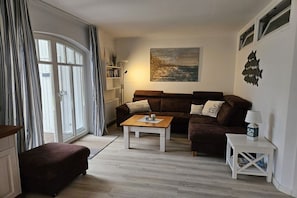 A living room with a sofa, a coffee table, a side table, and a painting on the wall. - Holiday apartment with 2 bedrooms (Wittenbeck\/Kühlungsborn)