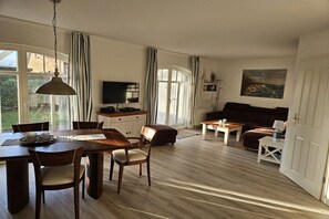 A spacious living area with a dining table, chairs, a sofa, and a television. - Holiday apartment with 2 bedrooms (Wittenbeck\/Kühlungsborn)