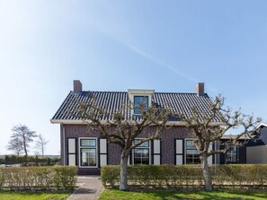 A modern two-story house with a tiled roof, brick walls, and a small front garden with young trees. - "t Hof van Schouwen (Burgh-Haamstede)
