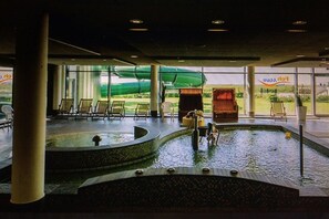 Ein Poolbereich mit Liegestühlen, einem Whirlpool und einer Rutsche.