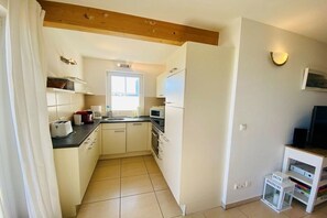A compact kitchen with white cabinets, a microwave, and a toaster. - Holiday apartment with 2 bedrooms (Sierksdorf)