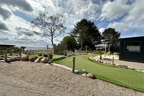 Un campo de golf con un putting green, búnkeres de arena y un puente de madera.