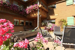 A wooden building with balconies, outdoor seating, and flower arrangements. - Holiday apartment with 2 bedrooms (Riezlern)