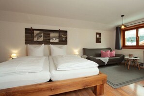 Ein Schlafzimmer mit Doppelbett, einer Couch, einem kleinen Tisch und einem Fenster mit Blick.