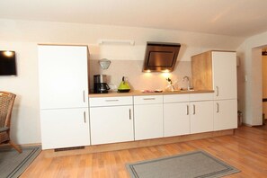A compact kitchen with white cabinets, a built-in stove, and a microwave. - Holiday apartment with 2 bedrooms (Riezlern)