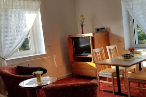 A cozy room with a television, a dining table, and a chair. - 1 in the house Traumweide (Oberwiesenthal)