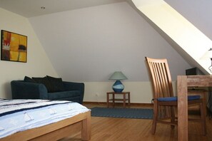A room with a bed, a sofa, a chair, a lamp, and a painting on the wall. - Holiday apartment with 2 bedrooms (Zinnowitz)