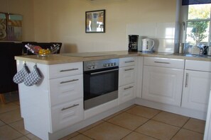 A kitchen with white cabinets, a stove, and a coffee maker. - Holiday apartment with 2 bedrooms (Zinnowitz)