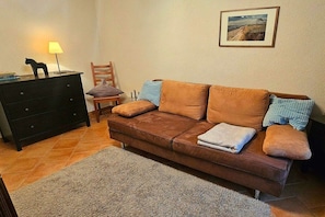 A living room with a brown sofa, a black dresser, a lamp, and a framed picture on the wall. - Holiday home with 2 bedrooms (Ostseebad Prerow)