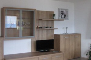 A modern living room with a flat-screen TV, wooden cabinets, and a glass-fronted cabinet. - Holiday apartment with 2 bedrooms (Zellberg)
