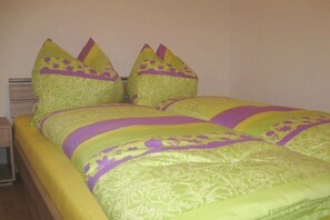 A bed with a green and yellow patterned bedspread and matching pillows. - Holiday apartment with 2 bedrooms (Zellberg)