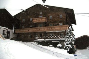 A multi-story wooden building with a balcony, surrounded by snow. - Holiday apartment with 2 bedrooms (Zellberg)