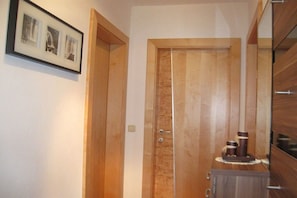 A hallway with a wooden door, a framed photo on the wall, and a small table with items on it. - Holiday apartment with 2 bedrooms (Zellberg)