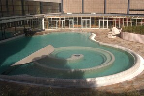 A swimming pool with a circular hot tub in the center, surrounded by a covered patio area. - Holiday home with 1 bedroom (Zinnowitz)