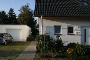 A residential house with a garage, a driveway, and a small garden area. - Holiday home with 1 bedroom (Zinnowitz)