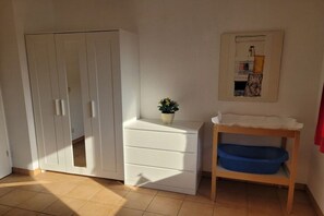 A room with a white wardrobe, a small white dresser, a blue basin on a wooden shelf, and a framed picture on the wall. - Holiday home with 1 bedroom (Zinnowitz)
