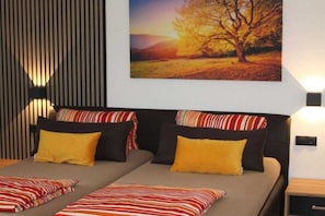 Uma cama de casal com travesseiros listrados e um quadro de uma árvore na parede.
