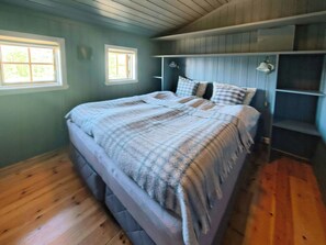 A bedroom with a bed, two windows, a headboard, and built-in shelves. - Traditional cabin with views over Setesdalen (Bykle)