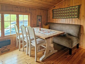 A wooden interior with a dining table, chairs, a sofa, and a patterned wall hanging. - Traditional cabin with views over Setesdalen (Bykle)