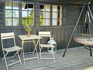 Un espace extérieur aménagé avec une table et deux chaises, un pot de fleurs et une lanterne.