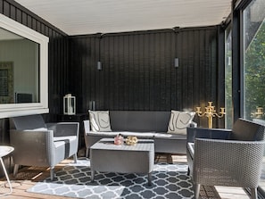 A modern outdoor seating area with wicker furniture, a patterned rug, and a view of greenery through large windows. - "Tordis" - 675m from the sea by Interhome (Gilleleje)