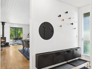 A modern interior with a fireplace, a dining area, and a wall-mounted coat rack. - "Tordis" - 675m from the sea by Interhome (Gilleleje)