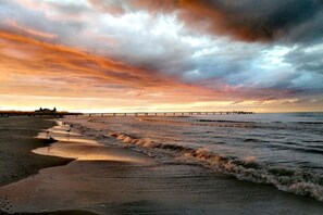 A beach with a pier extending into the water, waves gently lapping at the shore, and a dramatic sky above. - 12 in the Marinar forum (Seebad Heringsdorf)