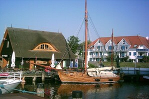 A wooden boat docked at a marina with a building featuring a sloped roof and a balcony. - Holiday apartment with 2 bedrooms (Zingst)