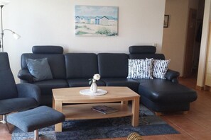 A living room with a black sofa, a wooden coffee table, and a blue rug. - Holiday apartment with 2 bedrooms (Zingst)