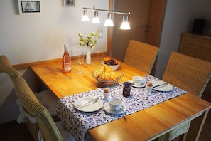 A dining table set with plates, cutlery, a bottle, a bowl of fruit, and a vase of flowers. - Holiday apartment with 2 bedrooms (Zingst)