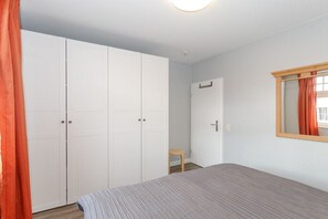A bedroom with a bed, a wardrobe, and a window with curtains. - Villa La Mer - No. 13 (Kühlungsborn)