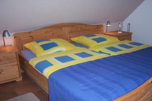 A bedroom with a wooden bed, two bedside tables, and a nightstand. - Holiday home with 3 bedrooms (Otterndorf)