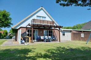 A two-story house with a covered patio area and a small garden. - Holiday home with 3 bedrooms (Otterndorf)
