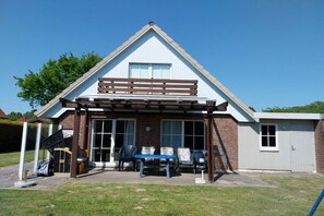A two-story house with a covered patio area, a garage, and a small shed. - Holiday home with 3 bedrooms (Otterndorf)