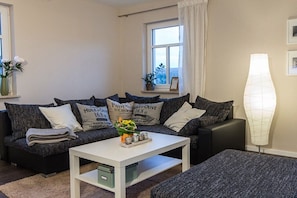 Ein modernes Wohnzimmer mit einer Sofagarnitur, einem Couchtisch und einer Stehlampe.