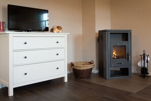 Una habitación con un aparador blanco, un televisor de pantalla plana, una chimenea y una cesta de mimbre.