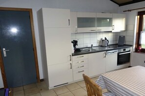 A compact kitchen with white cabinets, a black countertop, and a built-in oven. - Holiday home in Bredene with swimming pool (Bredene)
