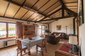A spacious living area with a dining table, chairs, a sofa, and a fireplace. - Holiday home in Bredene with swimming pool (Bredene)