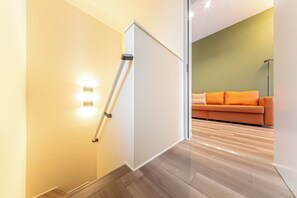 Ein modernes Interieur mit einer Schiebetür zu einem Wohnbereich, der eine Couch und eine Stehlampe beinhaltet.