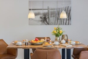 Une table de petit-déjeuner en bois, des chaises et un tableau accroché au mur.