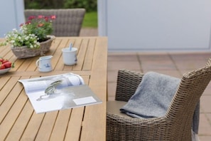 Une table en bois avec un magazine, une tasse et un panier de fleurs.