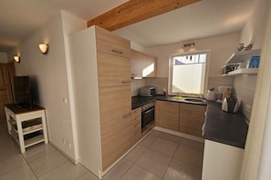 Eine moderne Küche mit Holzausstattung, einem Backofen und einem Fenster mit Jalousien.