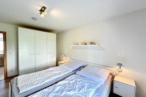 Ein Schlafzimmer mit Bett, Kleiderschrank, Nachttisch und einer Ablage mit Dekoration.