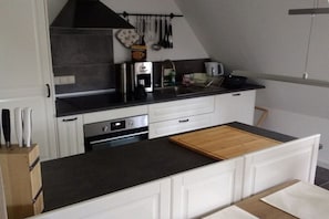 A modern kitchen with white cabinetry, a black countertop, and a wooden cutting board. - Holiday apartment with 2 bedrooms (Nottfeld)